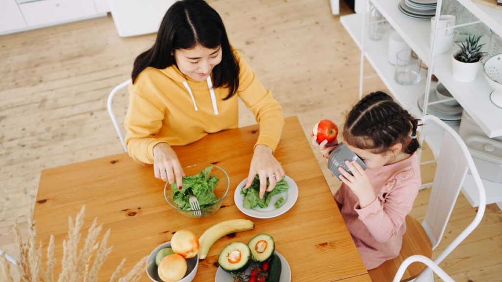 mother and daughter sitting at a table with food