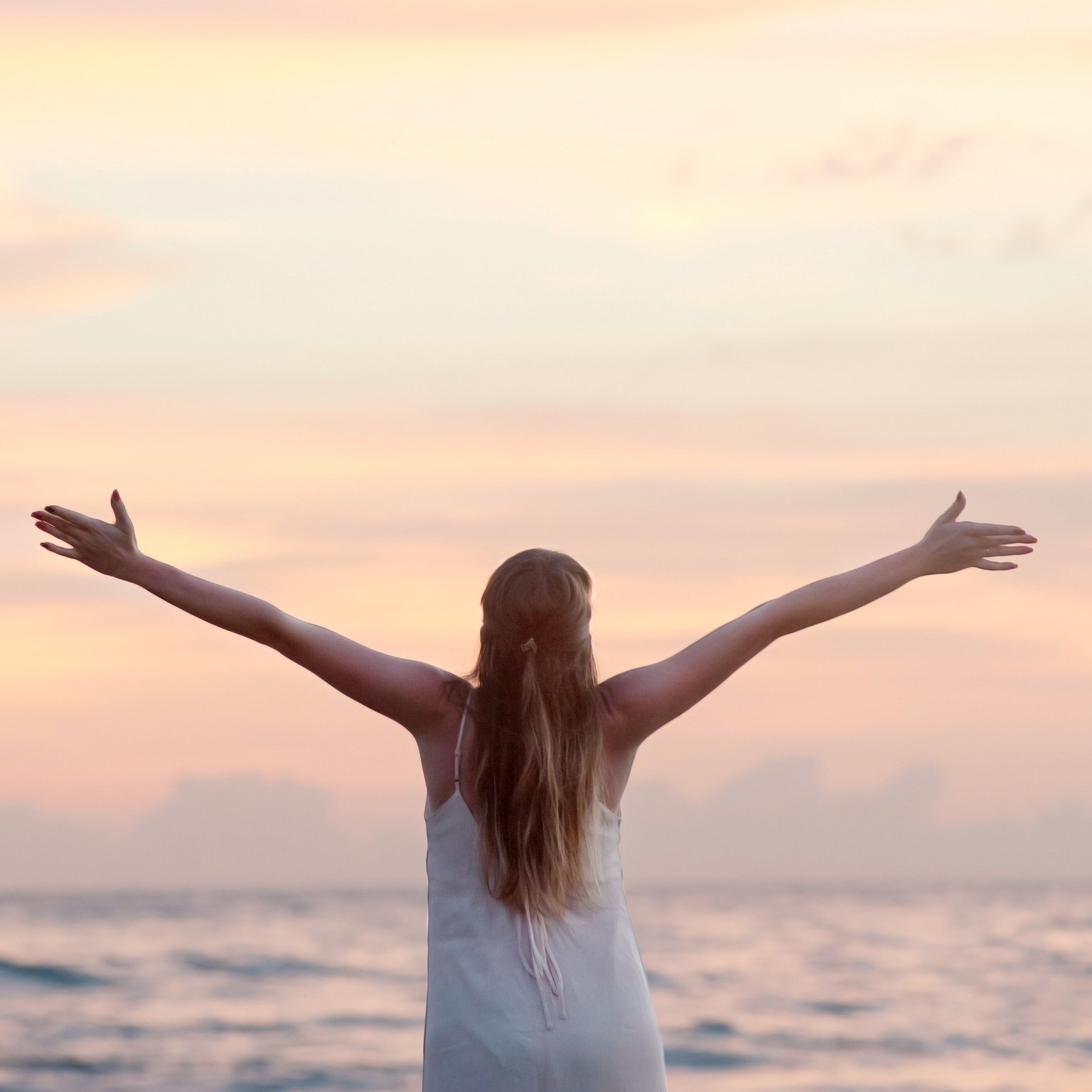 Woman with arms lifted skyward at the beach